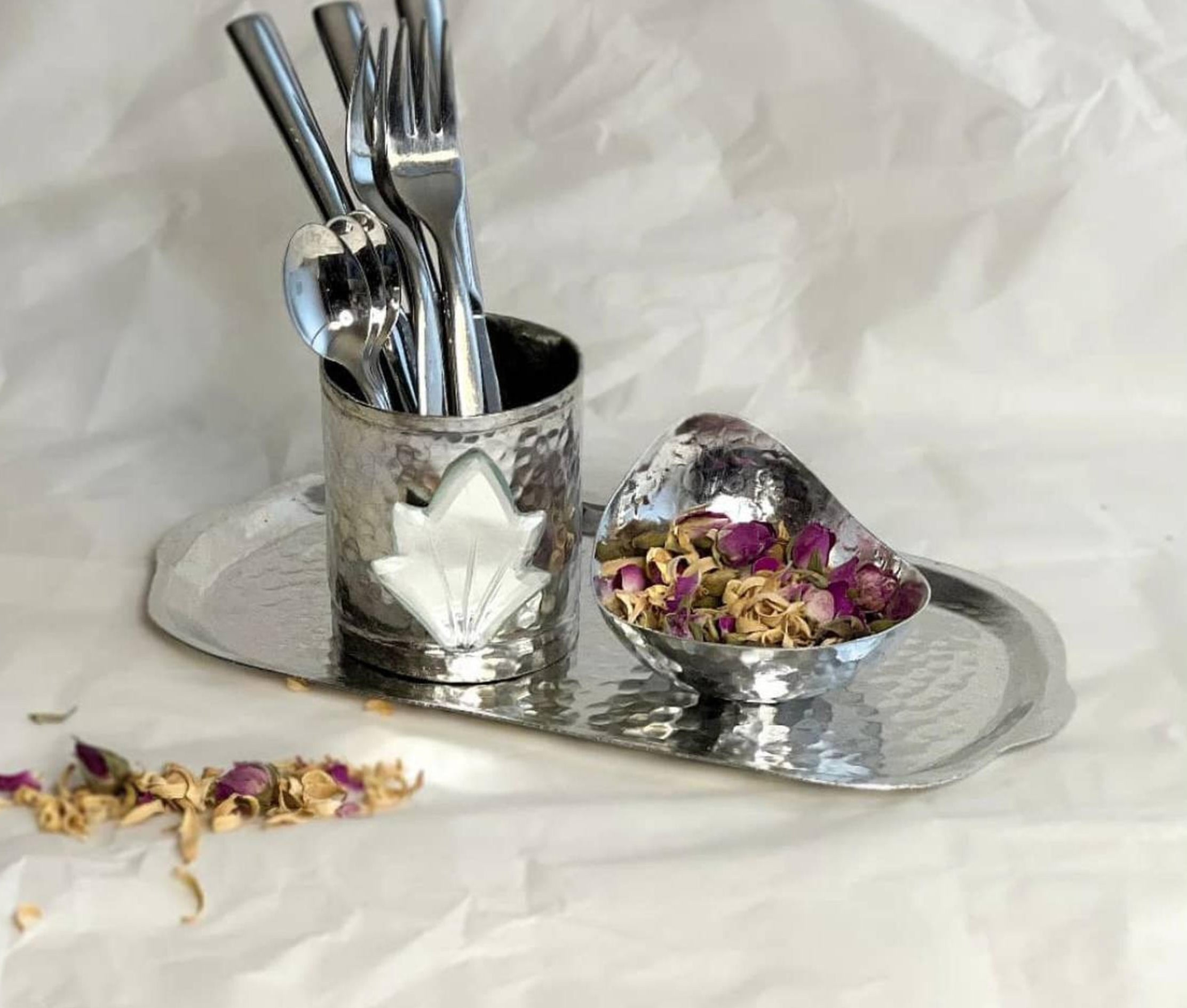 Hand-hammered cutlery holder with mirror inlay displayed on tray with pink roses