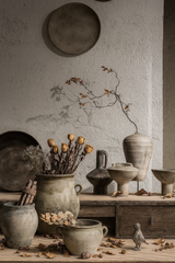 Vintage ceramic vases with dried flowers on wooden cabinet