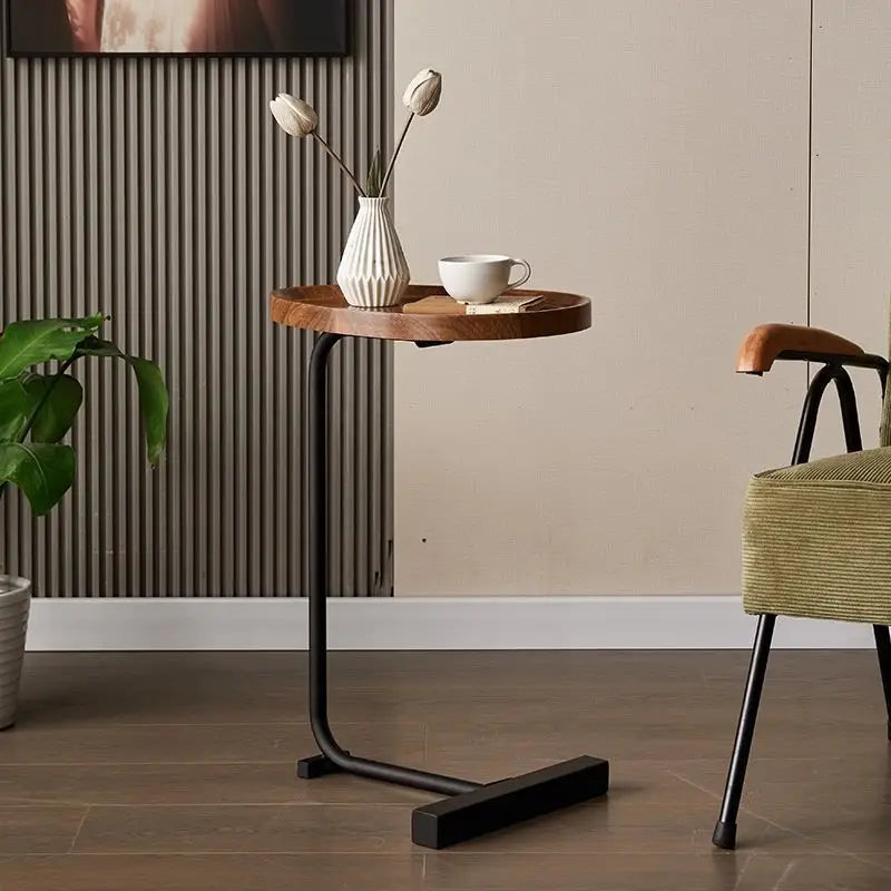 Small round wooden table with a black metal base in a room setting.