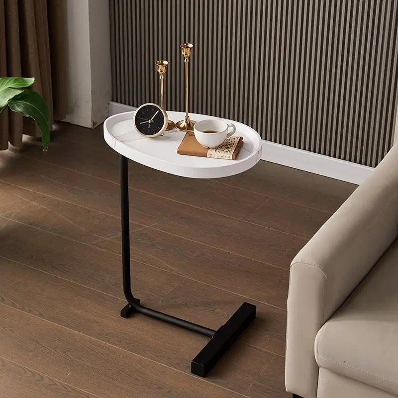 Small round white table with black legs in a room with a couch and decorative items.