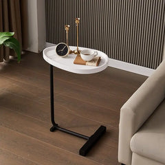 Small round white table with black legs in a room with a couch and decorative items.