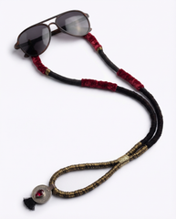 Sunglasses on a decorative cord with red and gold accents on a white background