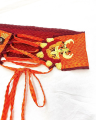 close-up of orange corset belt ties with crocheted leaf tassels