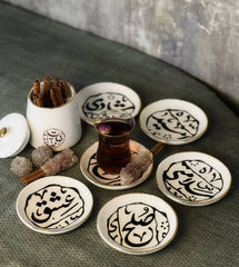 Single ceramic coaster with black calligraphy and gold rim