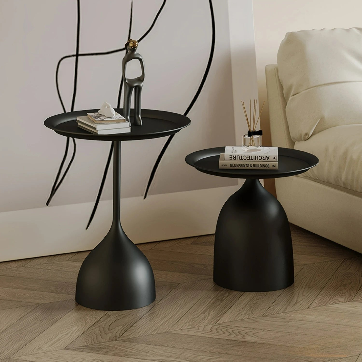 Two black side tables with decorative items in a living room setting.