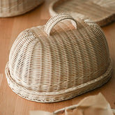 Handwoven rattan bread basket with lid on wooden table