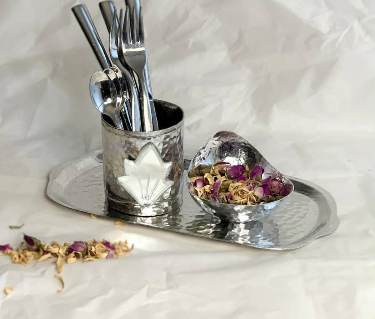 Hand-hammered cutlery holder with mirror inlay displayed on tray with pink roses