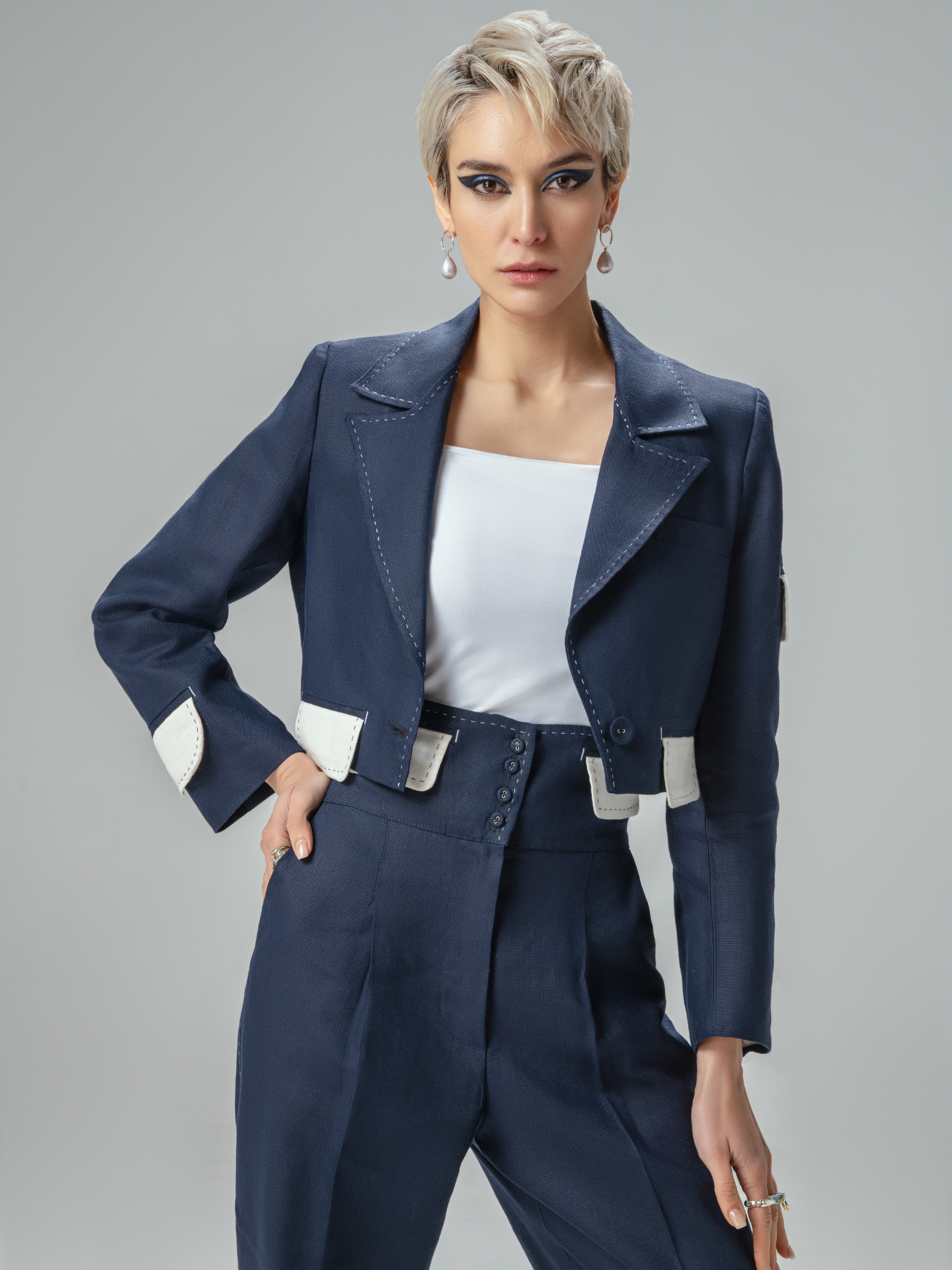 Close-up of decorative stitching on linen blazer and high-waisted pants