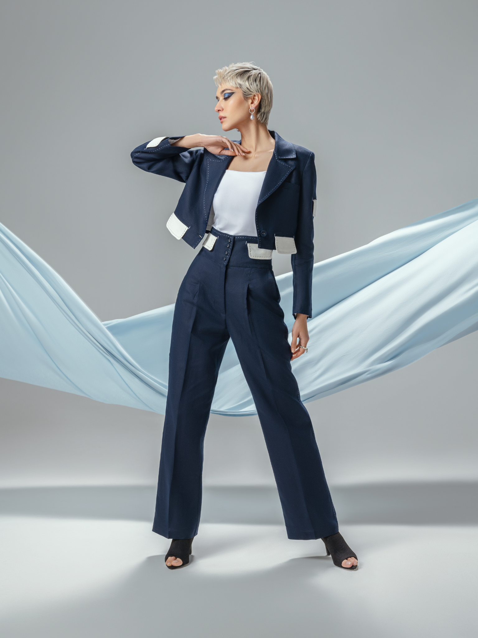 Woman wearing navy linen tailored suit with white patch details