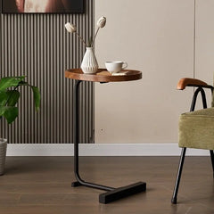 Small round wooden table with a black metal base in a room setting.