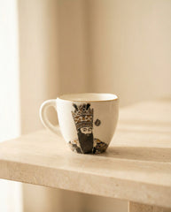 White mug with a decorative design on a beige surface