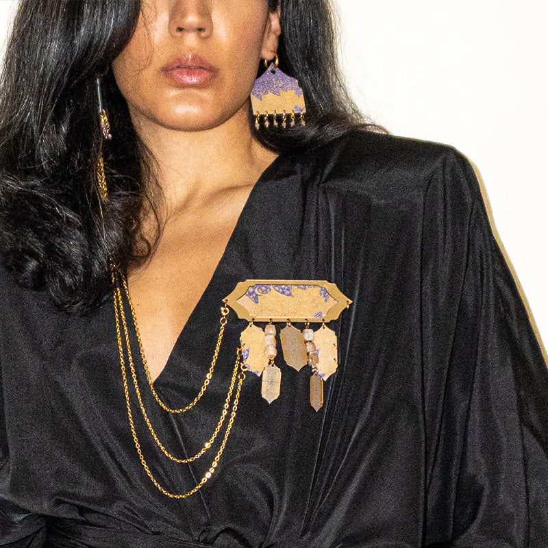 Woman wearing a black outfit with gold brooch 